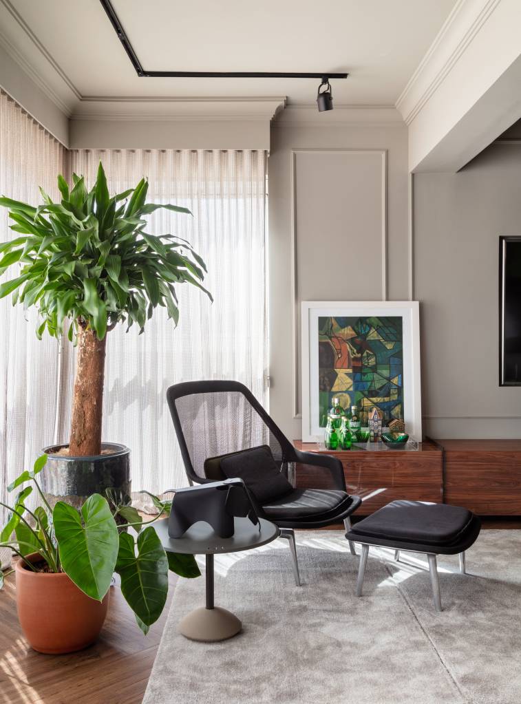 Sala com poltrona, plantas e parede com boiseries