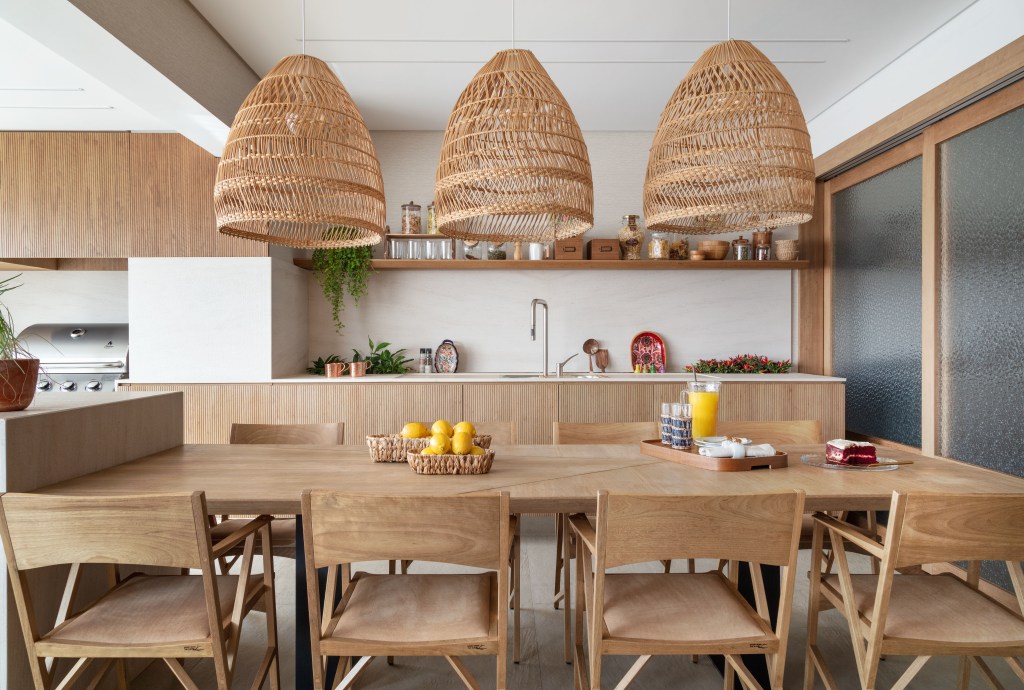 Área gourmet com mesa em madeira e luminárias de palha
