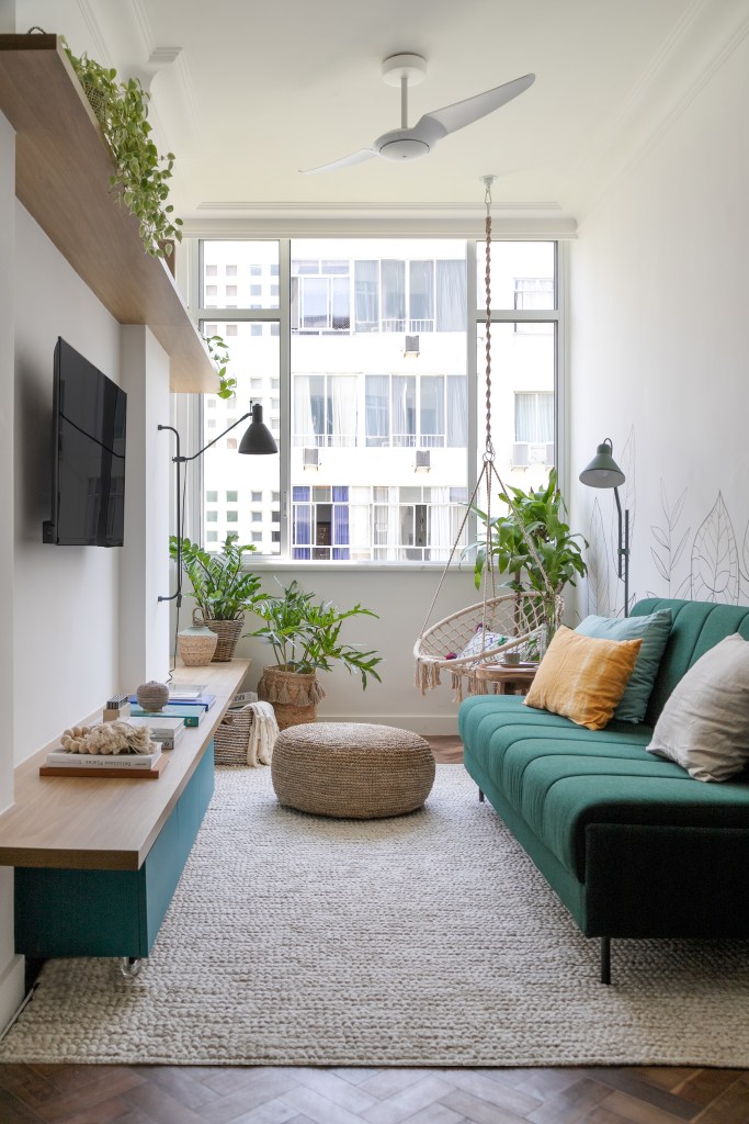 Sala pequena com sofá verde; pufe; plantas; tv