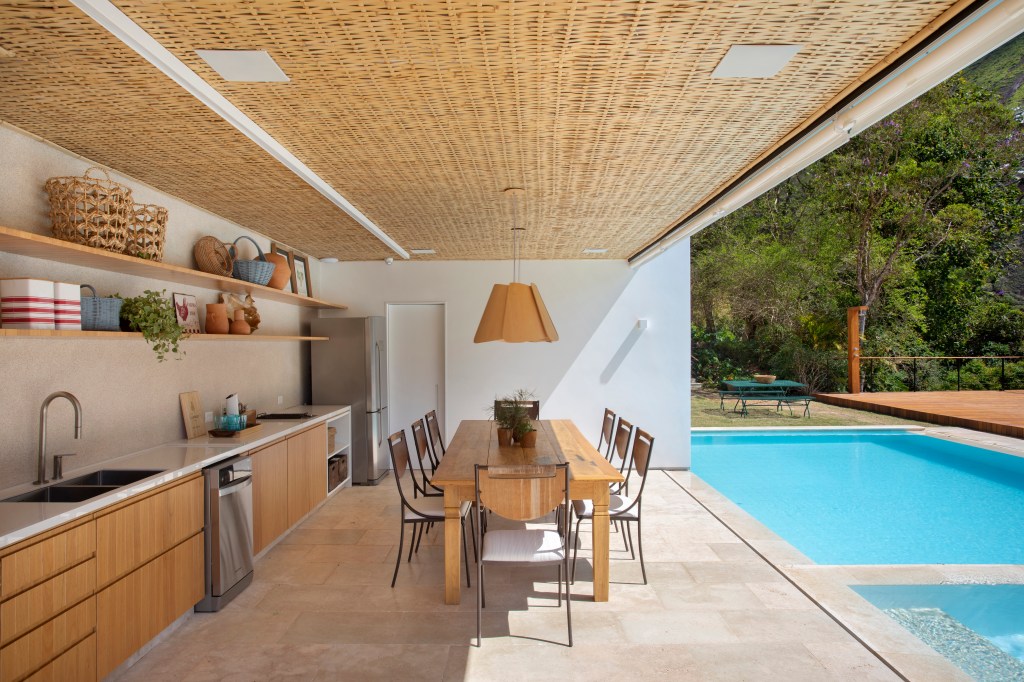 Área externa com espaço gourmet; piscina; mesa em madeira; luminária