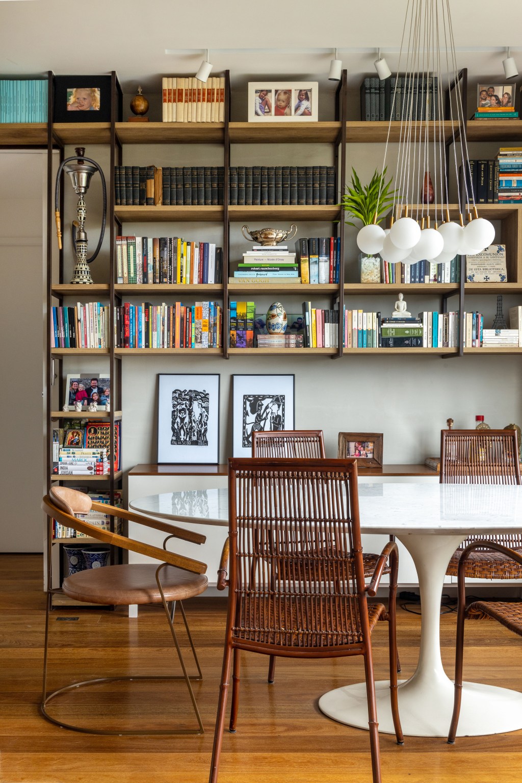Sala com escada; biblioteca; tapete colorido; poltrona Eames; mesa de jantar