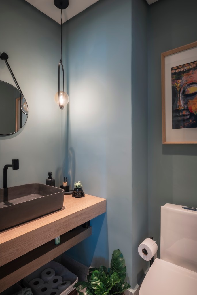 Banheiro com parede azul e espelho circular