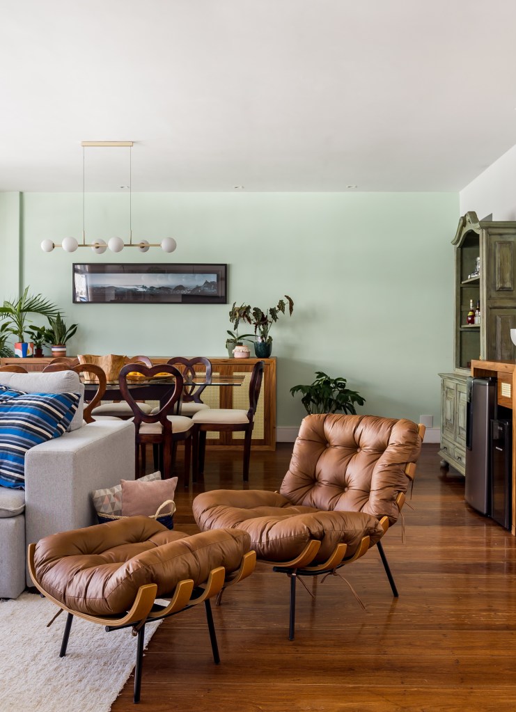 Sala de estar com poltrona, mesa de centro, plantas, parede verde