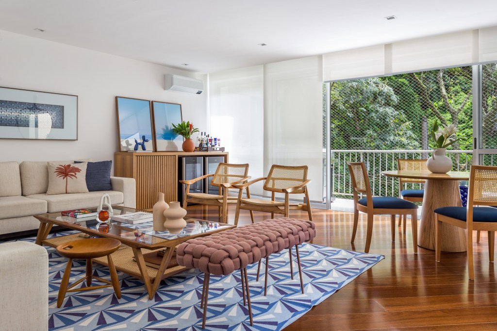 Sala de estar integrada com jantar; móveis em madeira e tapete azul geométrico