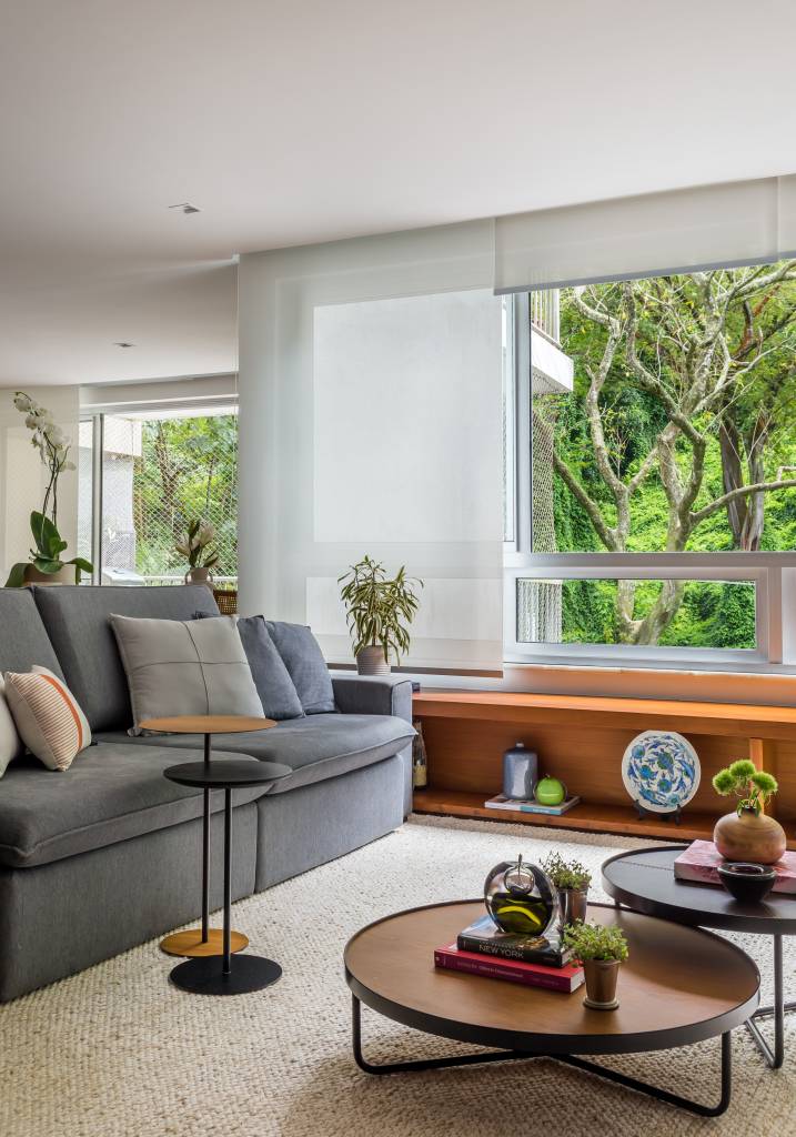 Sala de tv com sofá azul e mesas de centro