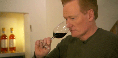 Conan O Brian cheirando uma taça de vinho