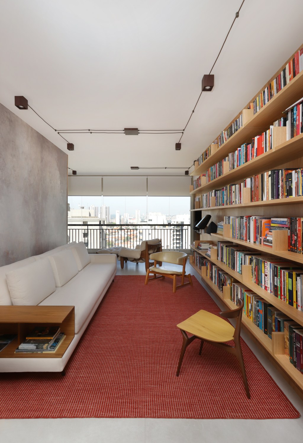 Sala de estar; estante; livros; poltrona; sofá branco; tapete vermelho
