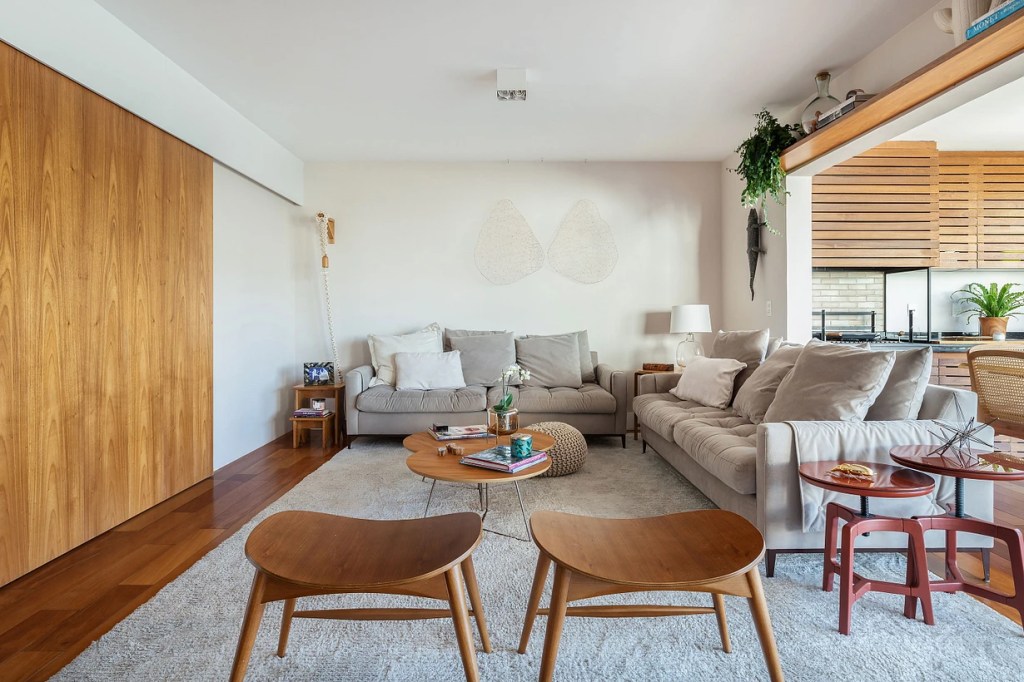 Sala de estar; bancos de madeira; sofá cinza; tapete