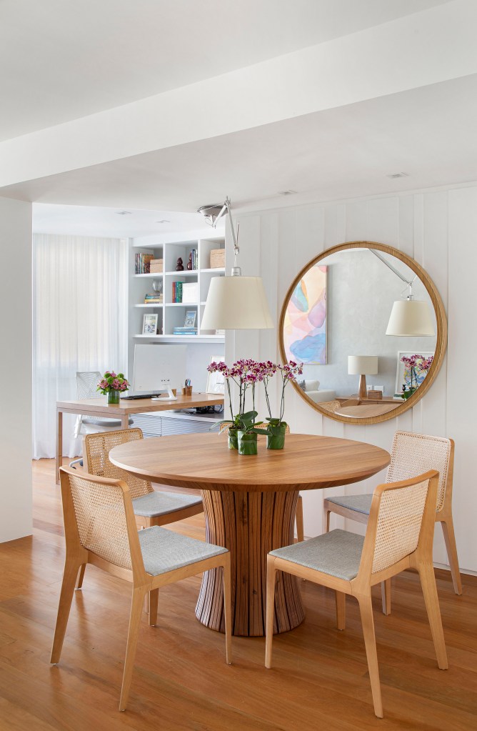 Sala de jantar; mesa redonda de madeira; espelho circular; luminária branca