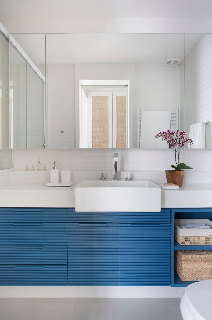 Banheiro com armário azul; bancada branca