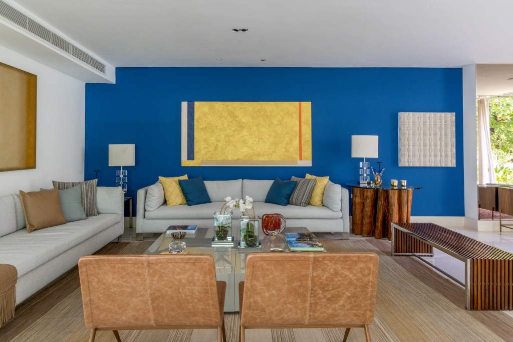 Sala de estar com parede azul; sofá cinza