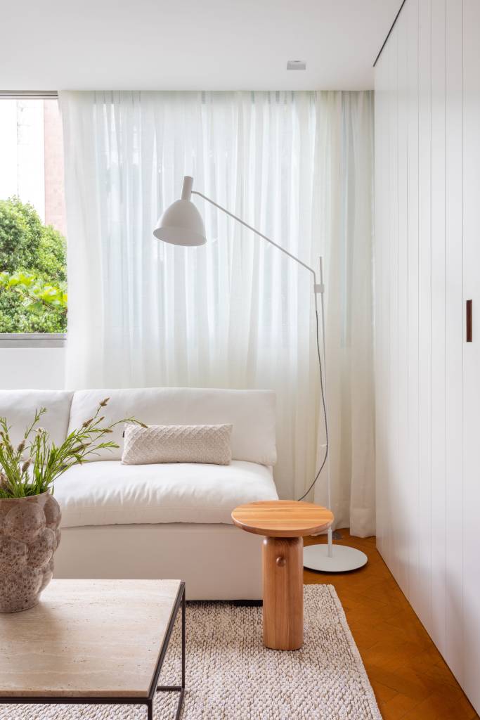 Sala de estar; sofá branco; luminária de piso; mesinha de centro