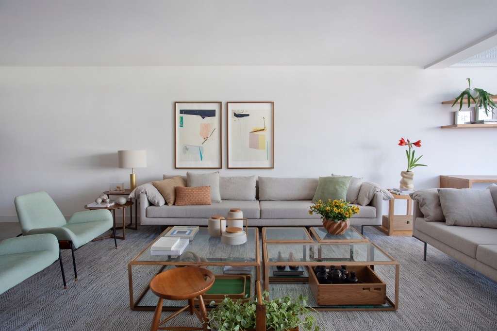 Sala de estar; sofá cinza claro; quadros; mesa de centro; mesa lateral; poltrona verde clara