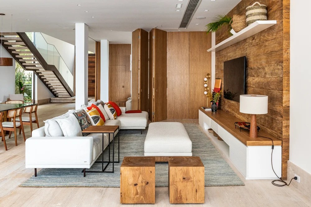 Estante de madeira; sala de estar; sala de tv; sofá branco; pufe branco