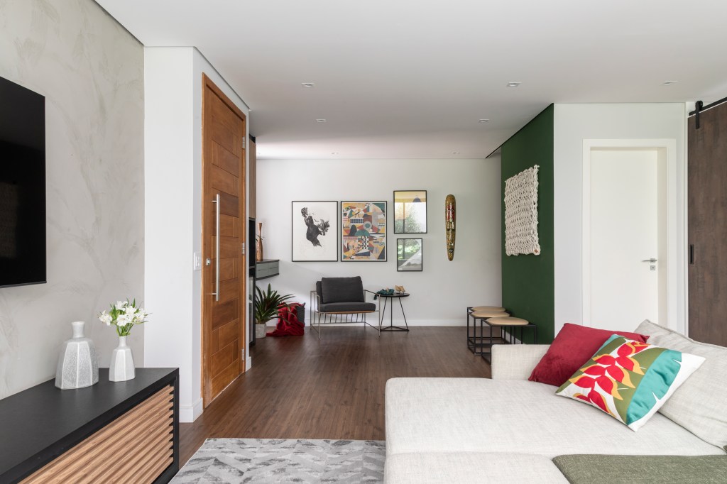 Sala; piso de madeira; parede verde; poltrona; quadros