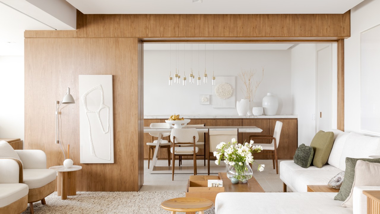 Sala de estar; poltrona branca; tapete; madeira; porta de correr de madeira; mesa de centro; sala de jantar