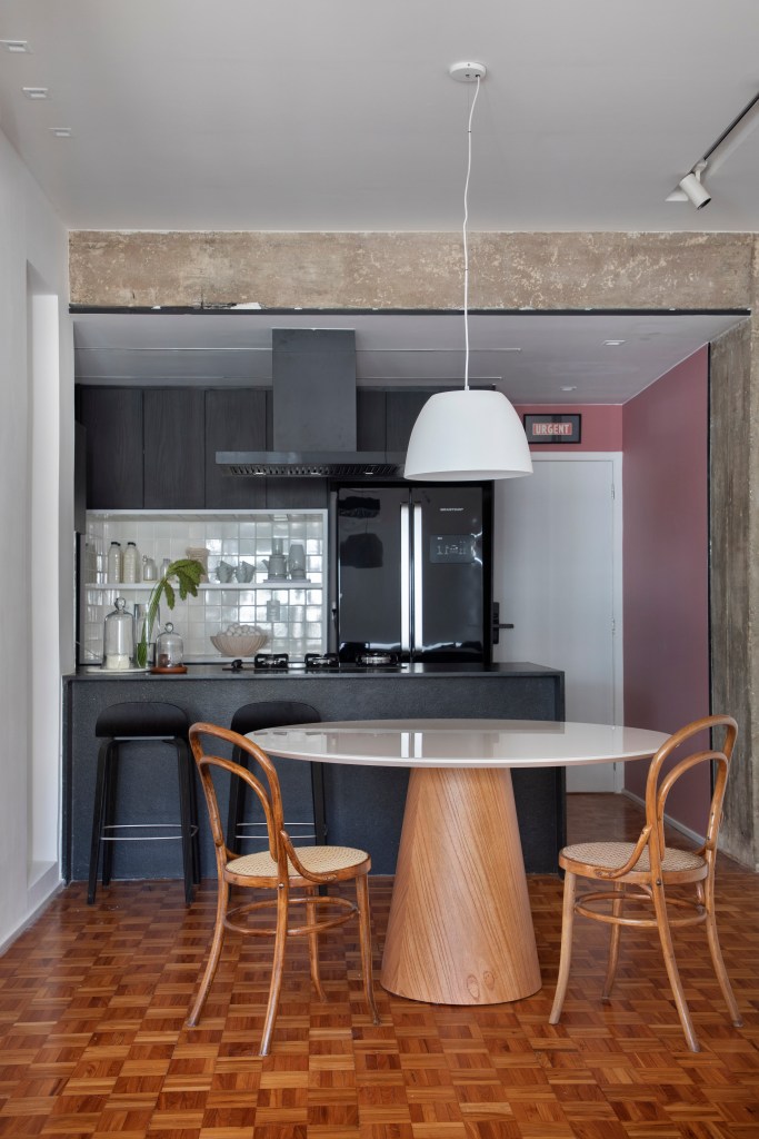 Sala estar; sala de estar integrada com cozinha; sala de estar integrada com jantar; viga de concreto aparente; mesa redonda; cozinha preta; cozinha preta e branca