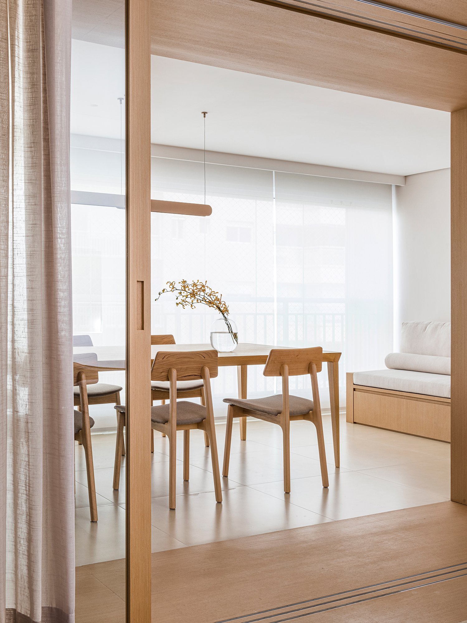 Apê minimalista de 110m² ganha pórtico de madeira entre varanda e sala