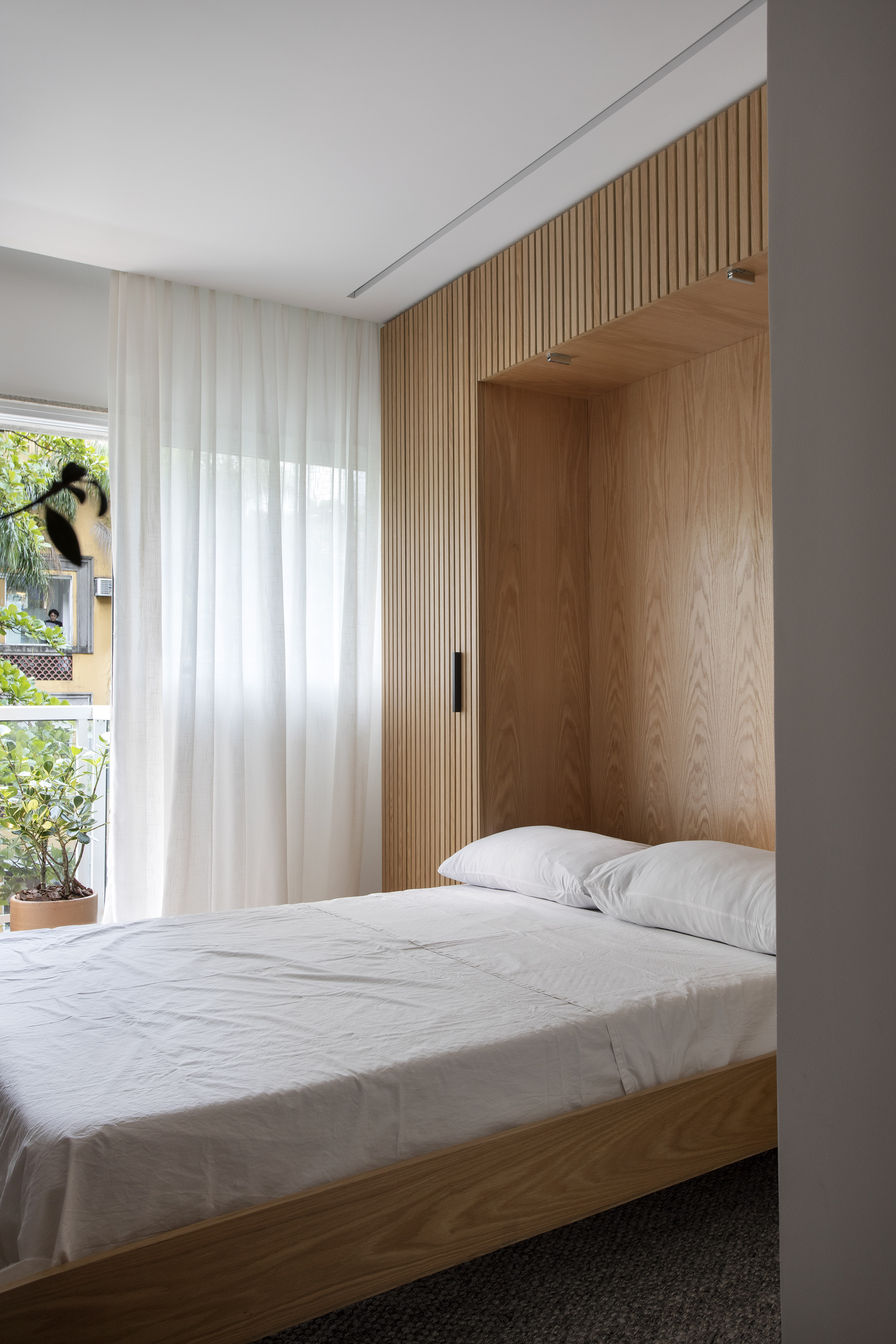 Apê de 160m² tem cama retrátil “escondida” em painel de madeira ripada