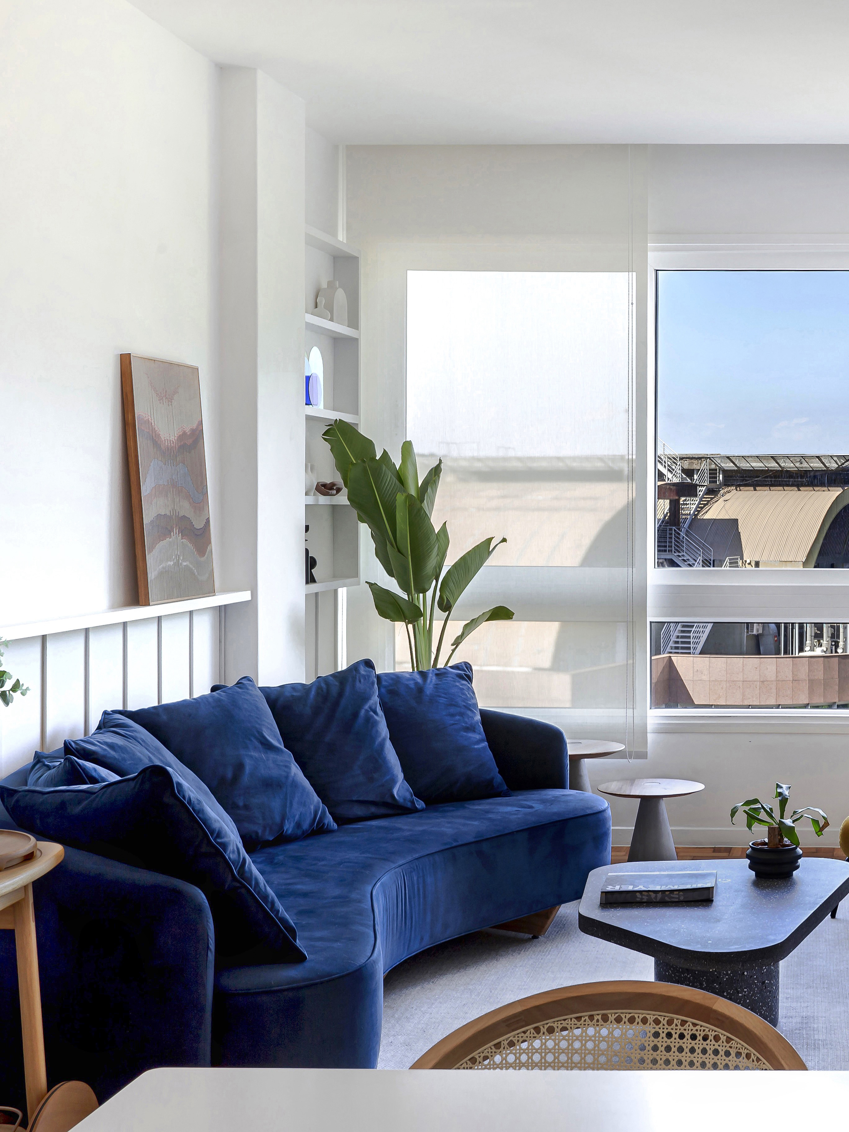 Sala de estar; sala de estar clara; sofá azul marinho; sofá curvo; boiserie; janela; mesa de centro