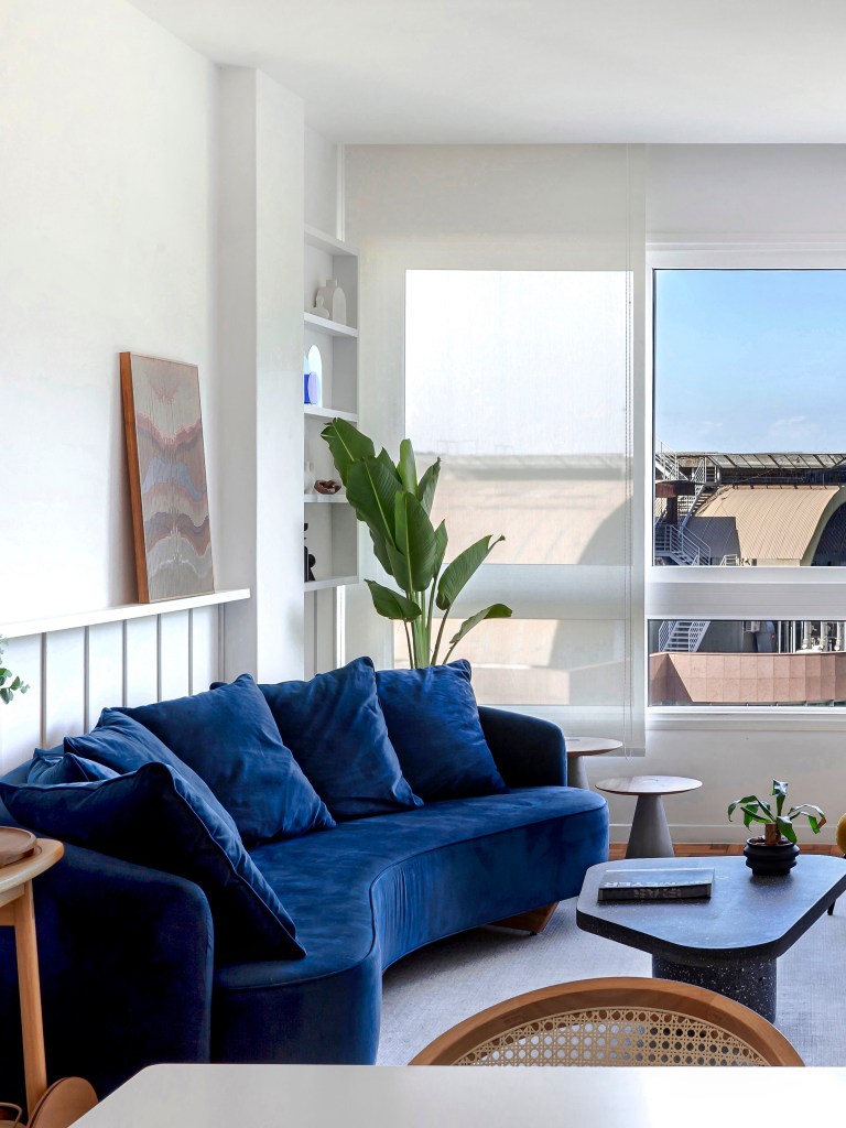 Sala de estar; sala de estar clara; sofá azul marinho; sofá curvo; boiserie; janela; mesa de centro