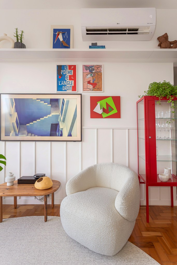 Sala de estar; poltrona branca; quadros; boiserie; luminária de parede