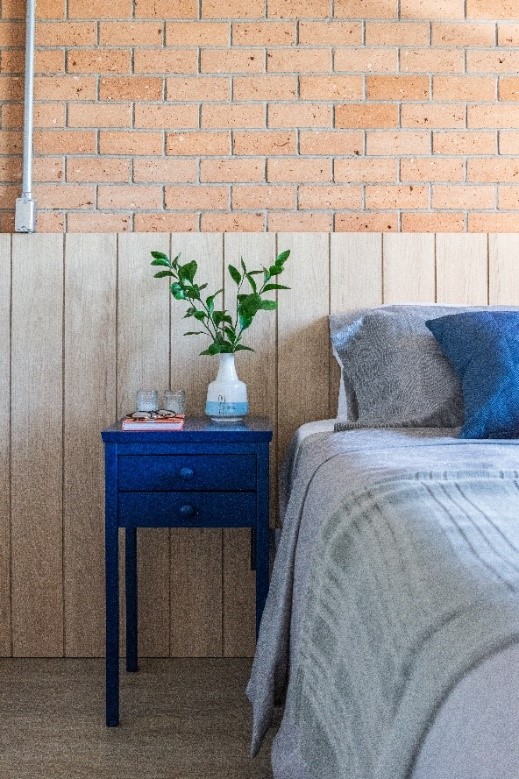 Quarto; cama; cabeceira de madeira; lambri; mesa lateral azul