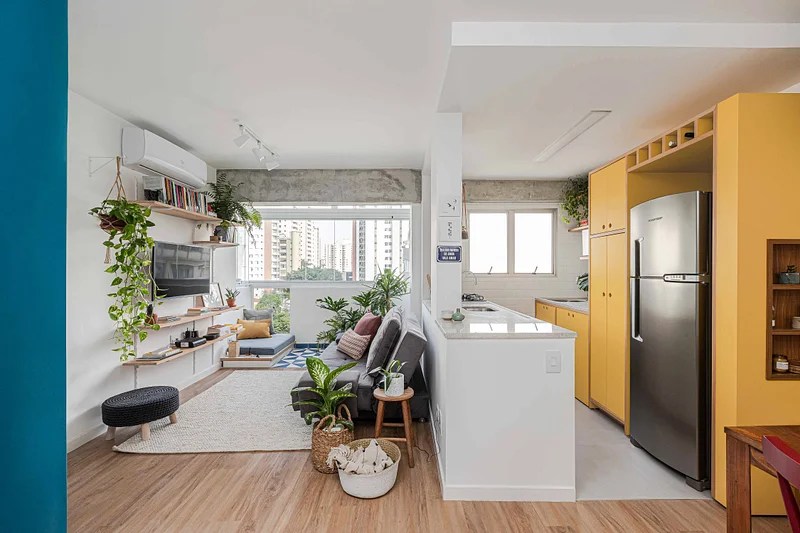Cozinha integrada; cozinha americana; cozinha integrada com sala; armários amarelos; bancada branca; sala de tv