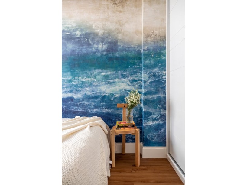 Mural azul na sala e bancada cimentícia na cozinha são destaques neste apê