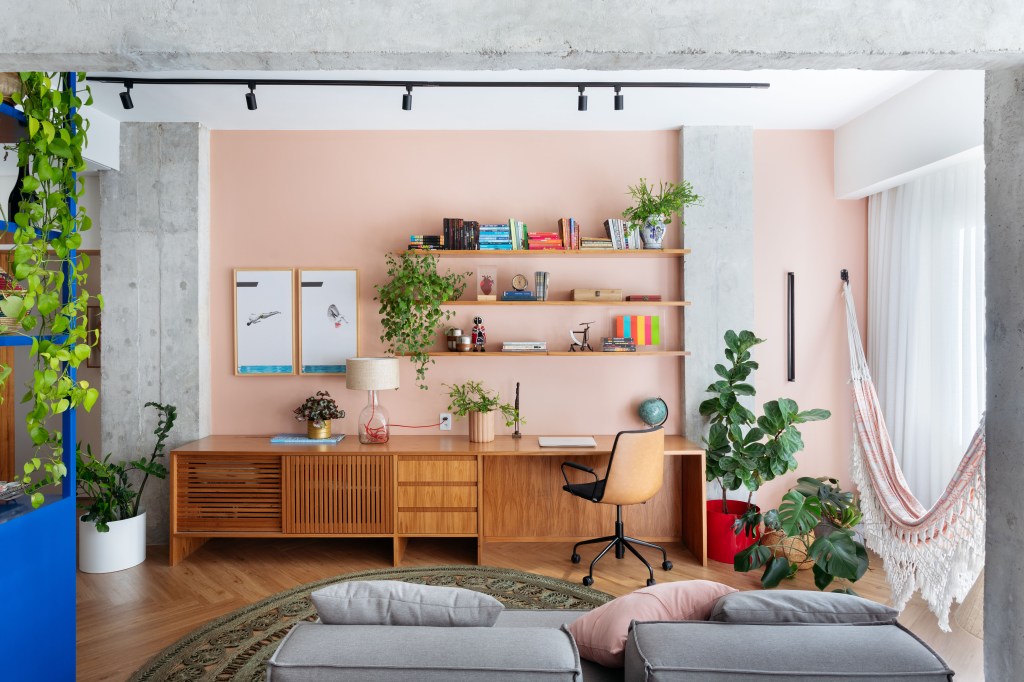Home office; home office na sala; trilho de spot; plantas; prateleira; sofá cinza