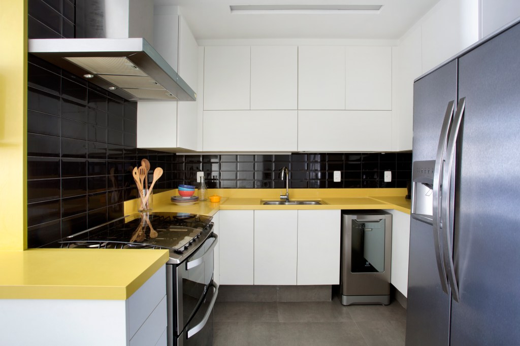 Cozinha; armário branco; bancada amarela; azulejo preto; backsplash