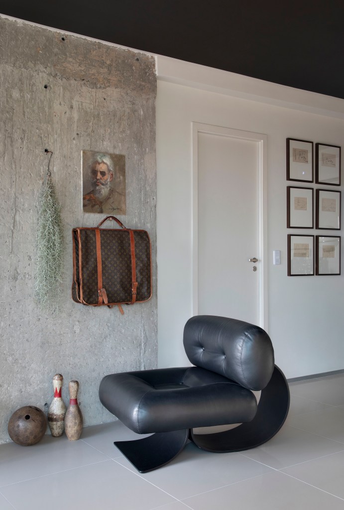 Sala de estar; paleta sóbria; parede de concreto; poltrona preta