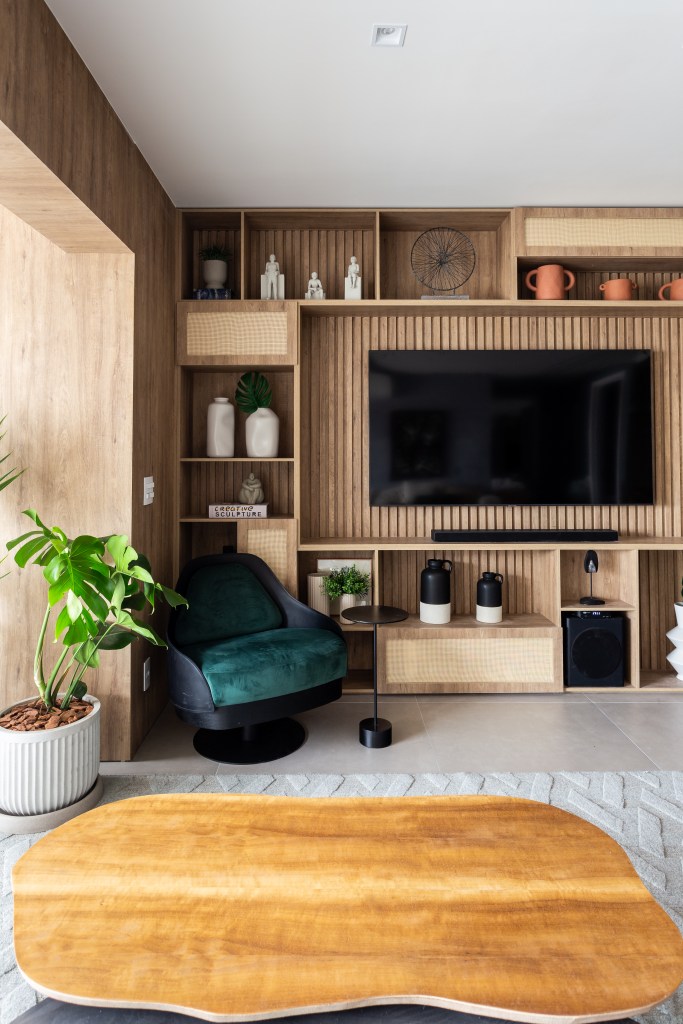 Sala de estar; sala de tv com painel de madeira ripada com nichos; poltrona verde