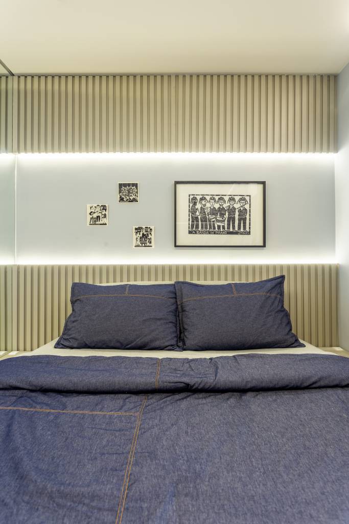 Quarto com parede de madeira ripada e nicho iluminado acima da cama.