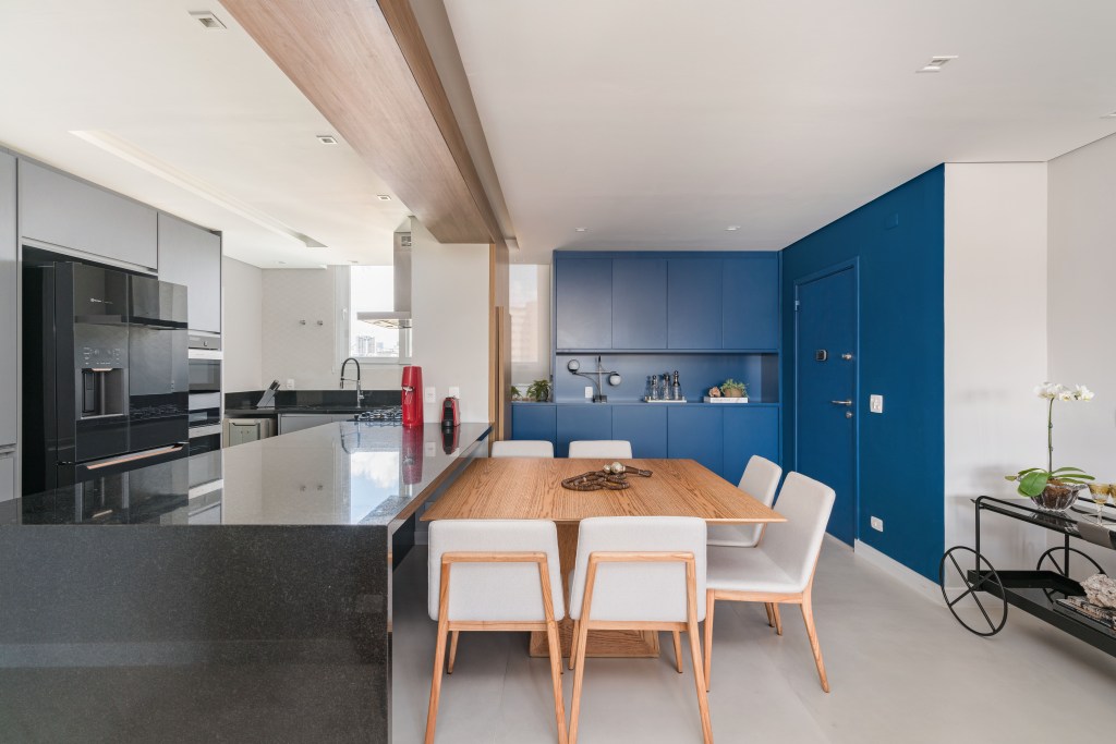 Cozinha; cozinha integrada; marcenaria azul; piso porcelanato; mesa de madeira; bancada de granito