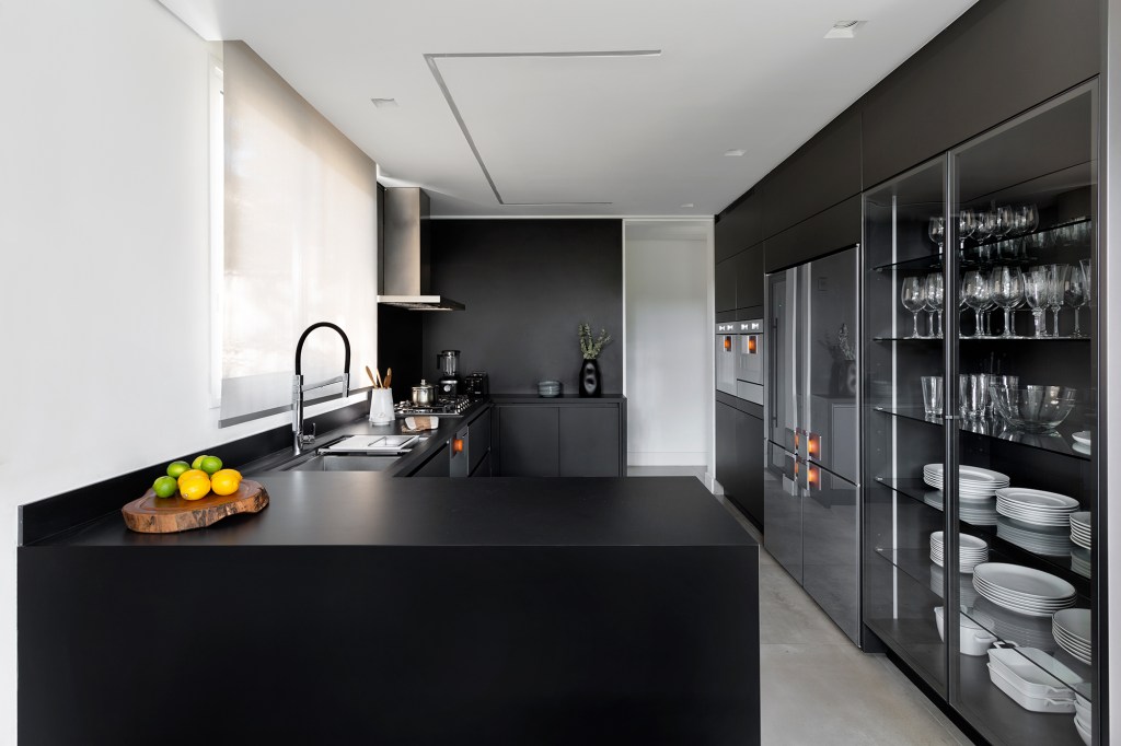 Casa 290 m² ganha cozinha preta com vista para jardim tropical Cadda Arquitetura decoração Carolina Haddad cristaleira marcenaria bancada