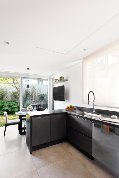 Casa de 290 m² ganha cozinha preta com vista para jardim tropical