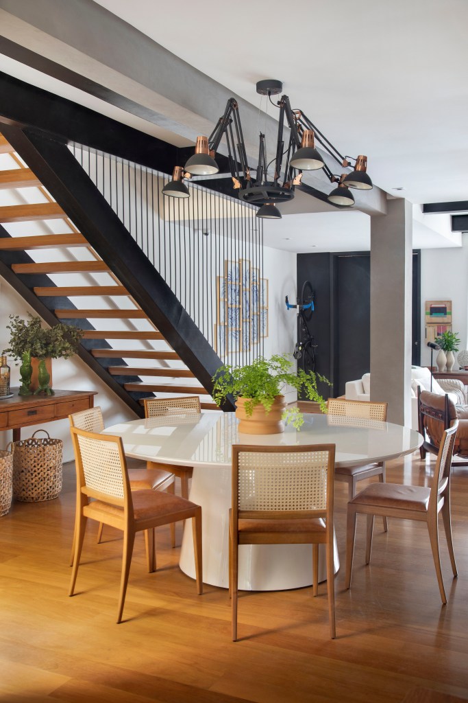 Sala de jantar; cozinha integrada; mesa de jantar branca redonda; piso de madeira; lustre industrial