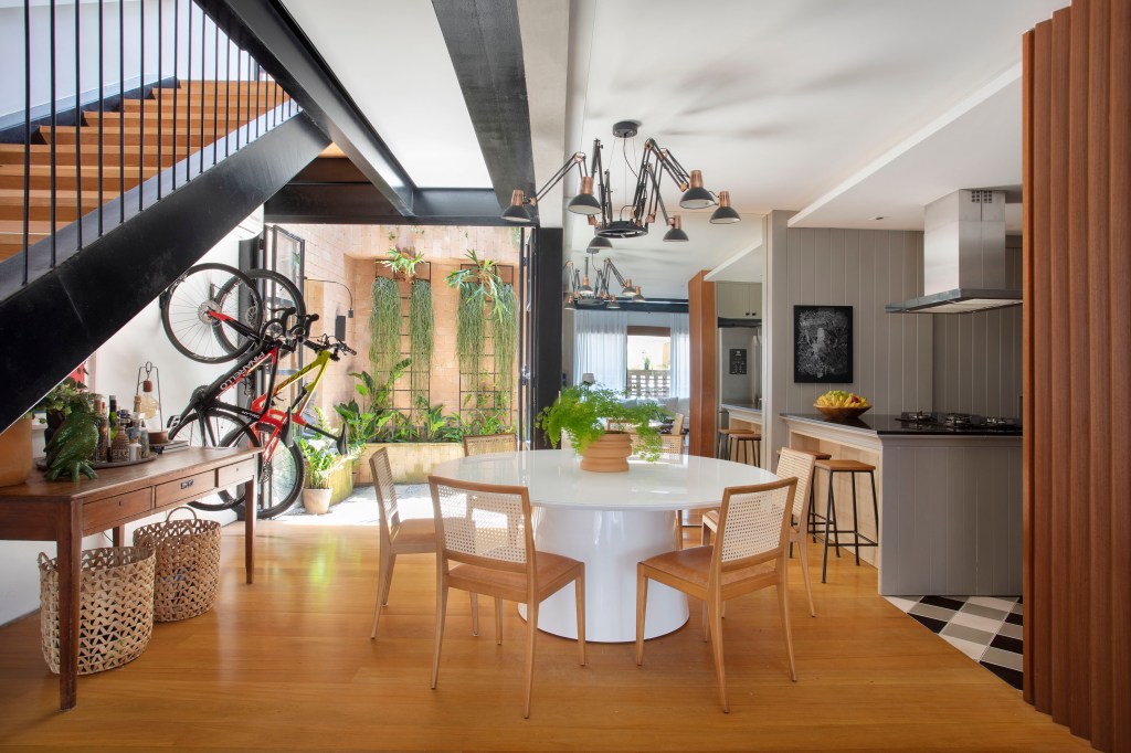 Sala de jantar; cozinha integrada; mesa de jantar branca redonda; piso de madeira; lustre industrial