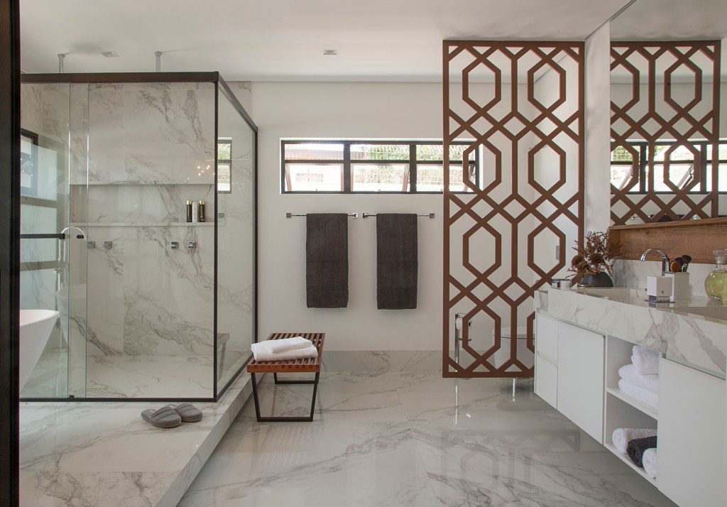 Banheiro revestido de mármore e box de vidra