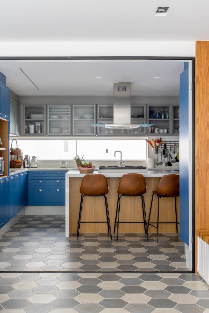 Cozinha com marcenaria azul; ilha de madeira com banquetas; piso geométrico