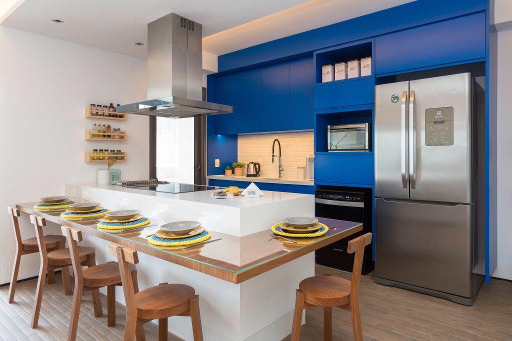 Cozinha; armário azul; bancada; ilha; cadeira de madeira; cozinha americana