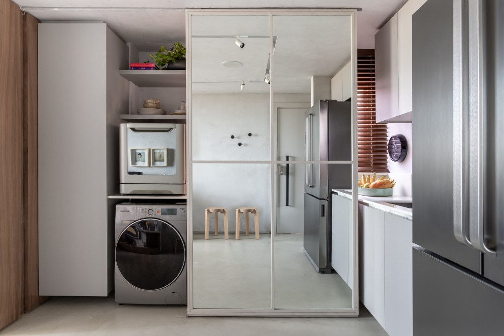 Lavanderia pequena integrada com cozinha atrás de porta de correr espelhada