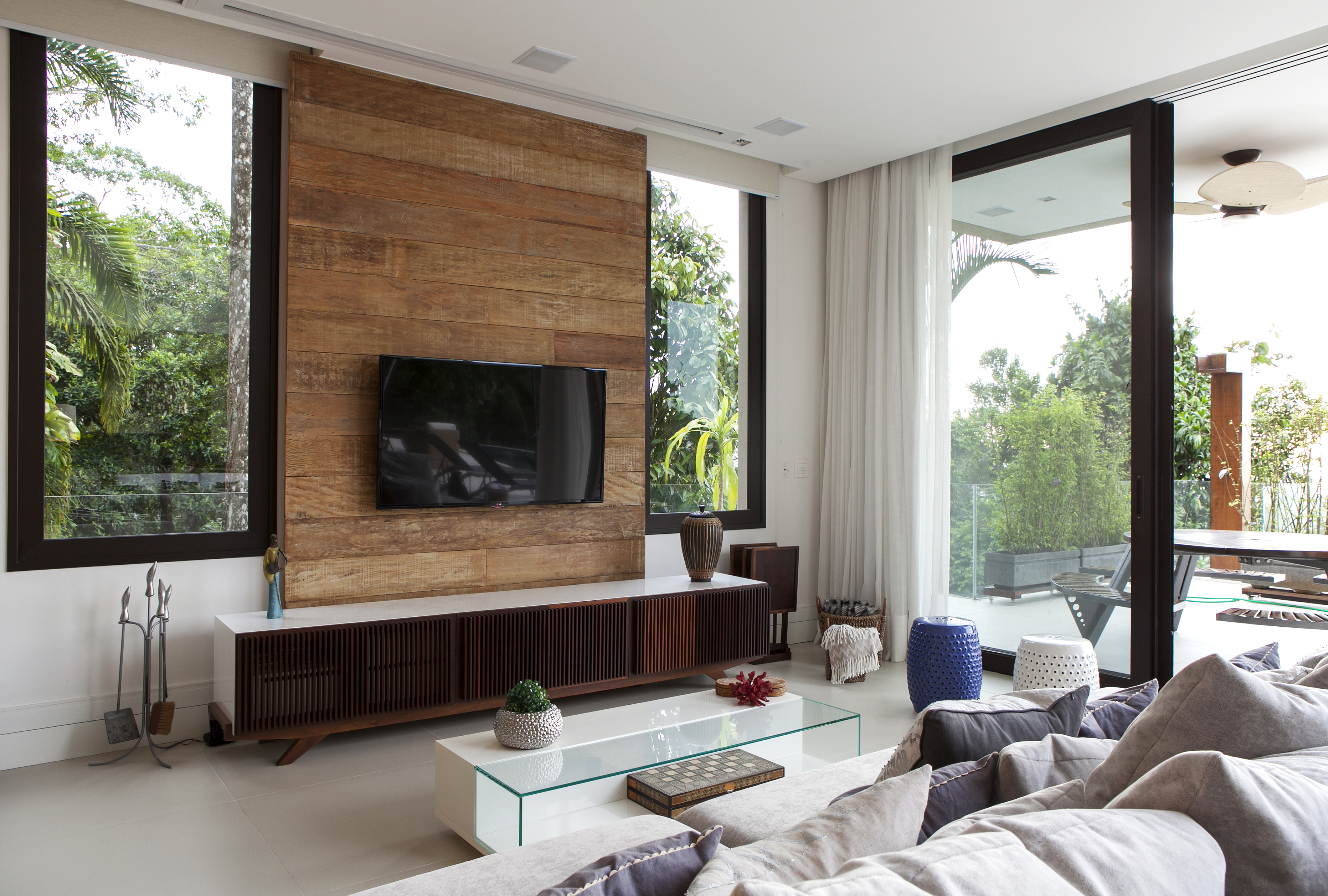 Sala de tv; sofá; painel de madeira; mesa de centro com tampo de vidro