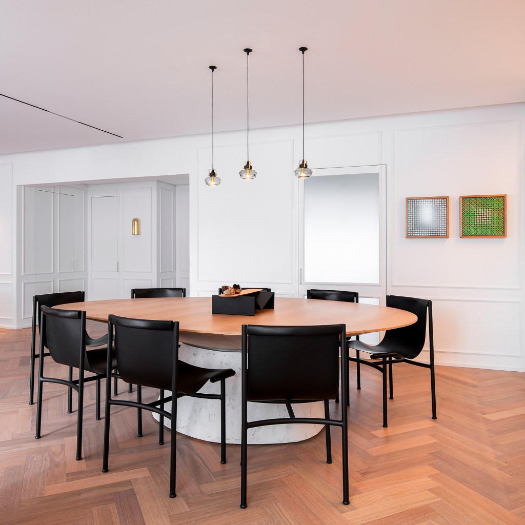 Apartamento ar parisiense movimento minimalista estilo nova-iorquino. Gabriela Casagrande sala de jantar mesa oval cadeiras preta boiserie quadro