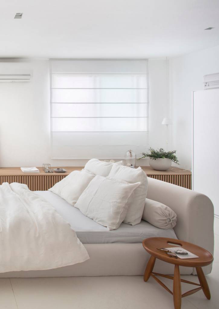 Cama baixa branca com cabeceira estofada.