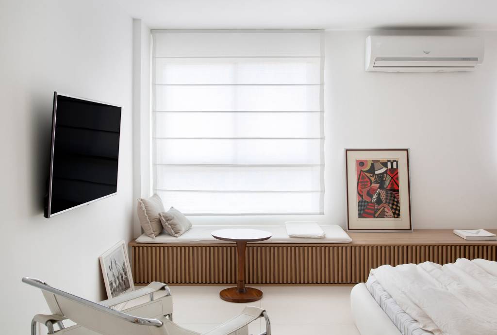 Loft branco com cama branca baixa e banco de madeira ripada
