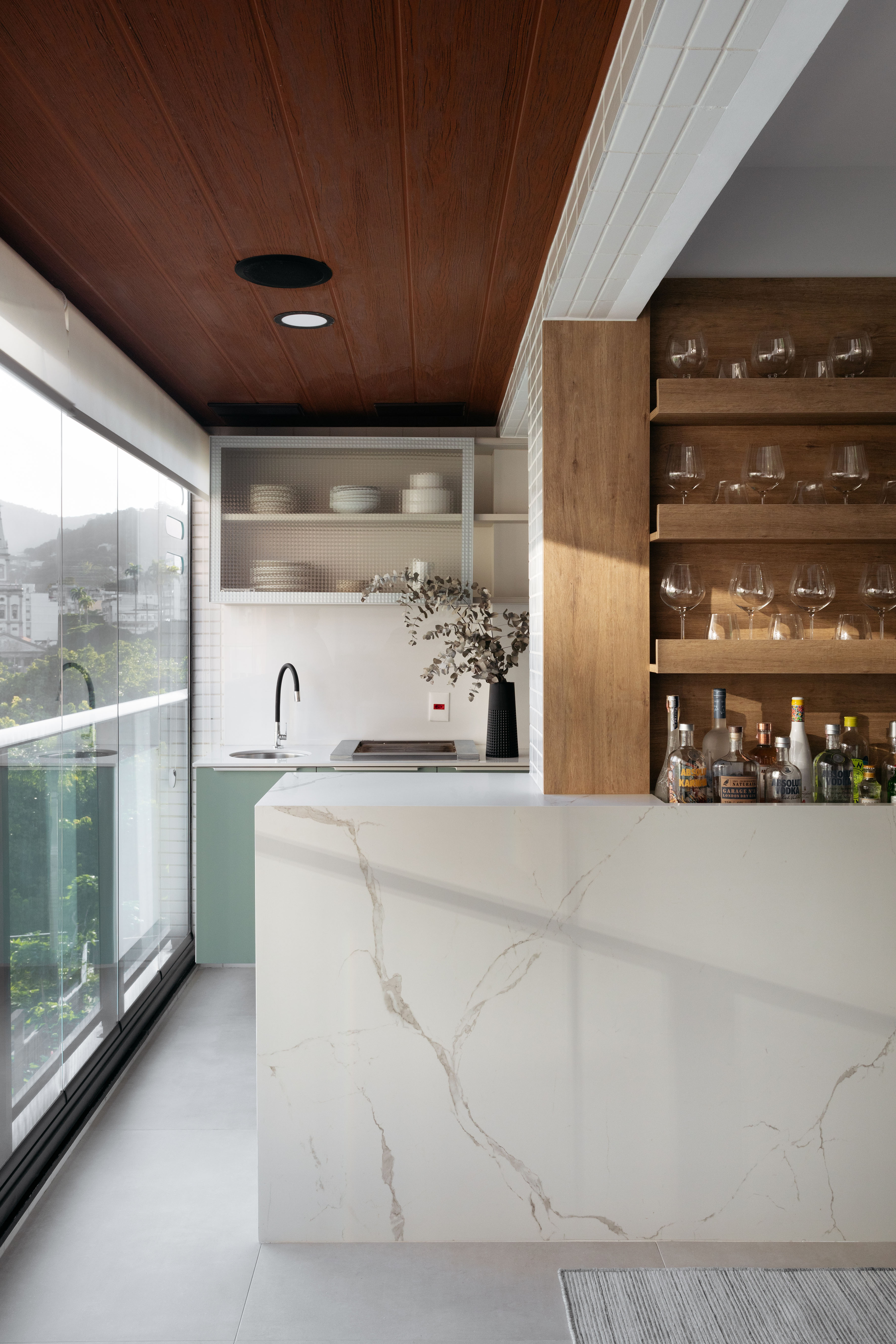 Bar integrado com bancada revestida de mármore e área gourmet pequena.