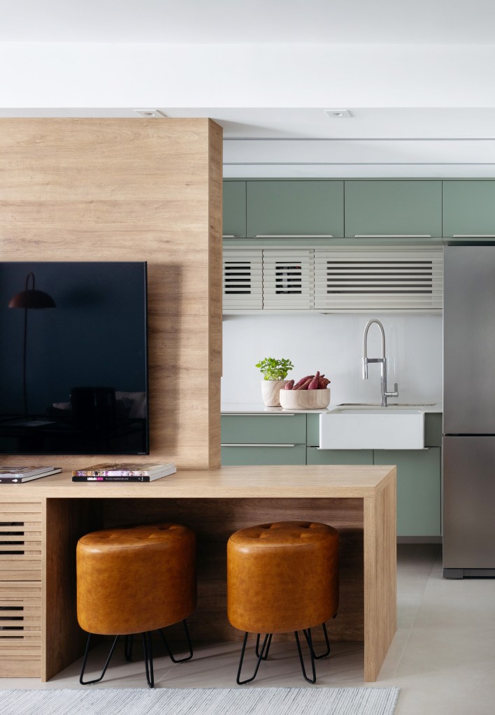 Cozinha integrada com marcenaria verde clara.