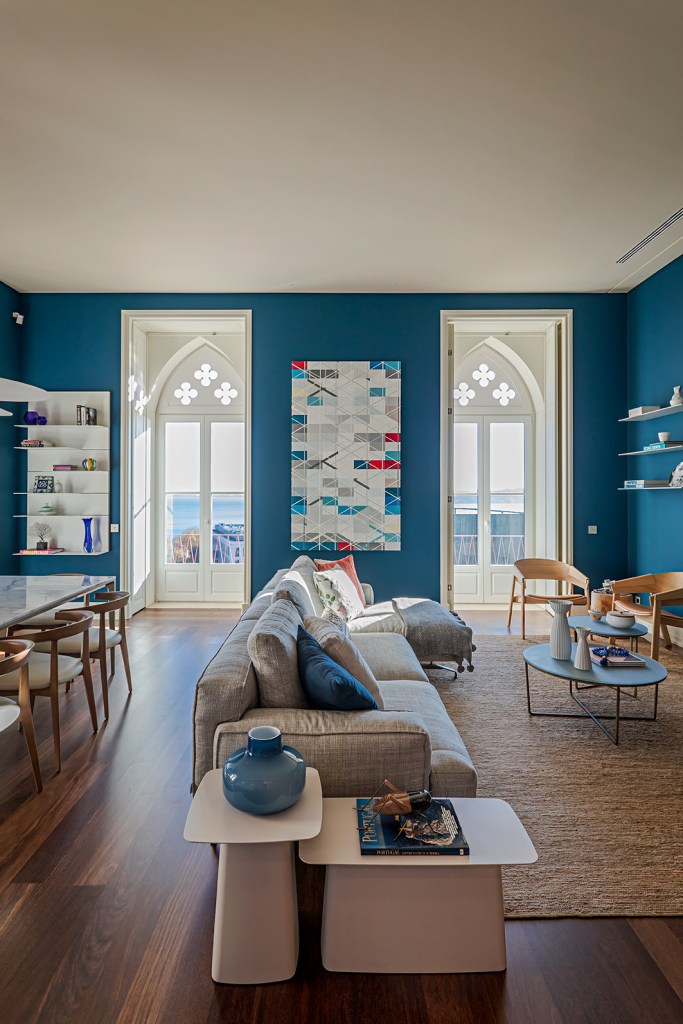 Sala de estar integrada com sofá cinza e paredes azuis.